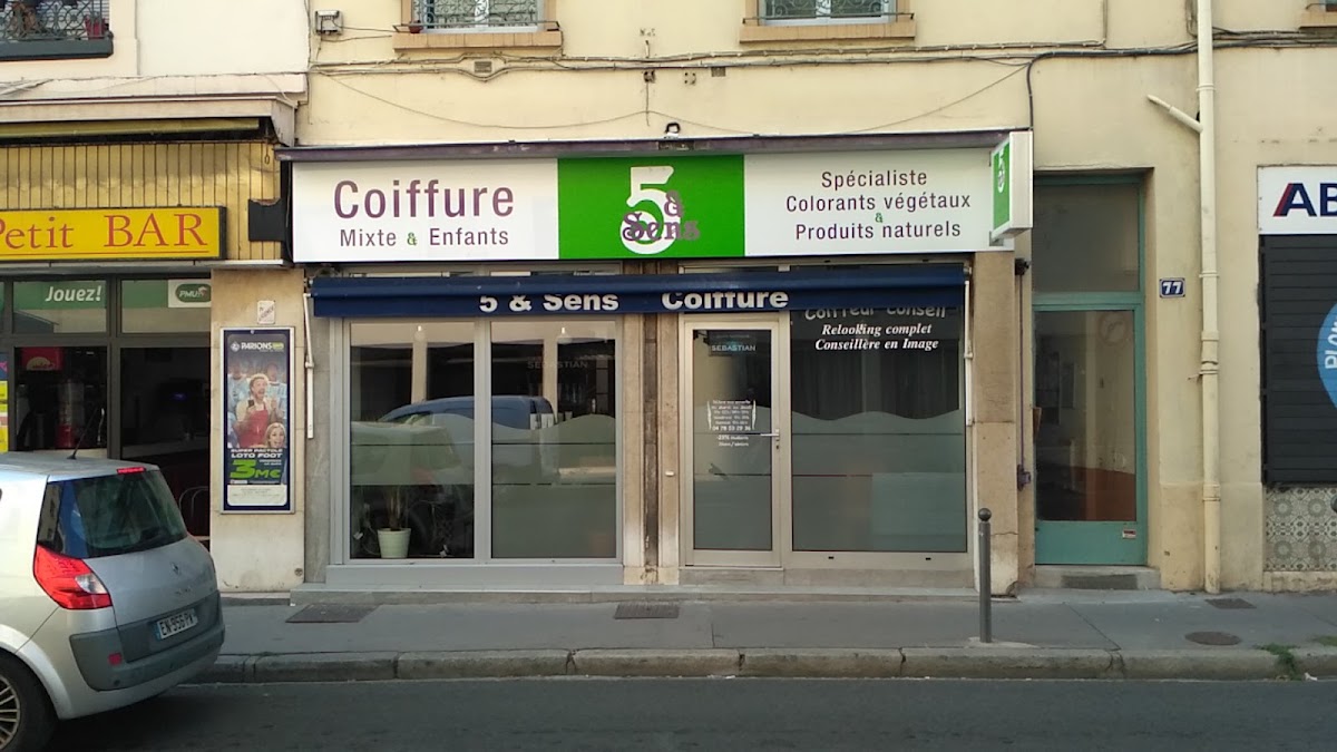 La façade du salon 5 & Sens au 77 rue du Dauphiné à Lyon, avec son enseigne verte, son store bleu marine et ses deux portes vitrées.